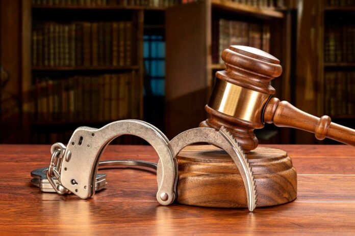 A,Pair,Of,Handcuffs,Rests,Against,A,Judge's,Gavel,And