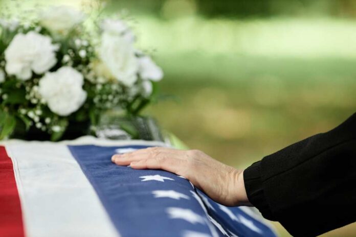 Close,Up,Of,Male,Hand,On,Coffin,Covered,With,American