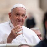 Pope Francis smiling and greeting people.