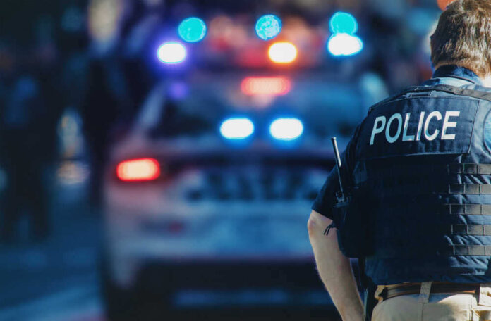 shutterstock_1543591088.jpg featured image Police officer and vehicle with flashing lights.
