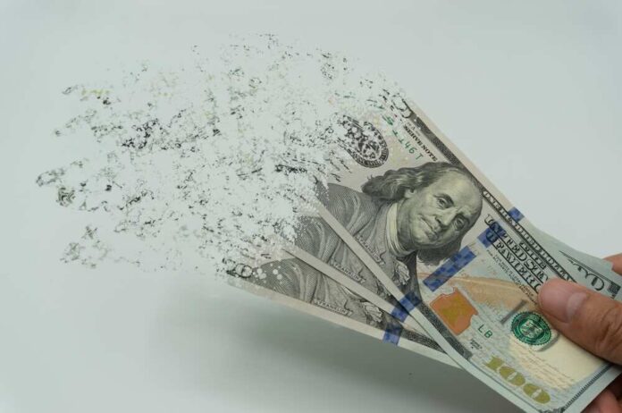 shutterstock_2122253927.jpg featured image Hundred-dollar bills disintegrating in hand.