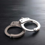 Metal handcuffs on a dark textured surface.