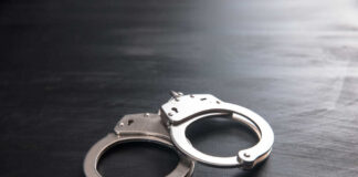 Metal handcuffs on a dark textured surface.