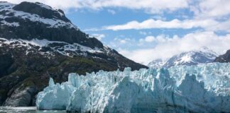 Glacier with mountains and cloudy sky in background