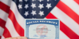 Hand holding social security card, American flag background.