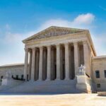 U.S. Supreme Court building exterior under blue sky.