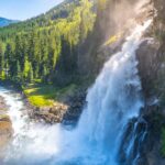 Waterfall cascading down mountain surrounded by dense forest