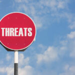 Red sign with the word threats against sky