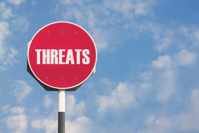 shutterstock_241274614.jpg featured image Red sign with the word threats against sky