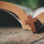 Open Bible with a wooden cross on it.