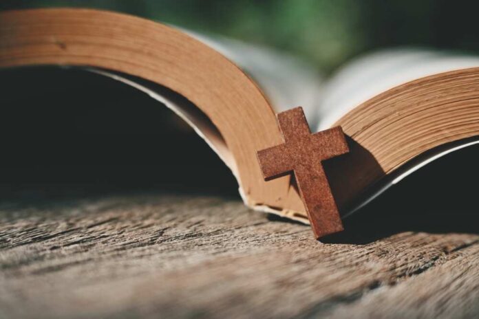 shutterstock_2422584703.jpg featured image Open Bible with a wooden cross on it.