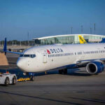 Delta airplane being towed at airport terminal gate