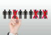 Hand crossing out stick figures with a red marker