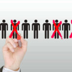 Hand crossing out stick figures with a red marker