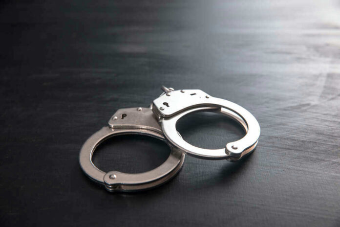shutterstock_1857504991.jpg Metal handcuffs on a dark textured surface