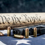 Gun and Constitution scroll on American flag