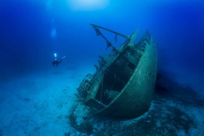 shutterstock_2198151971.jpg featured image Diver exploring a sunken shipwreck underwater scene