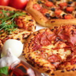 Three pizzas with various toppings and fresh ingredients