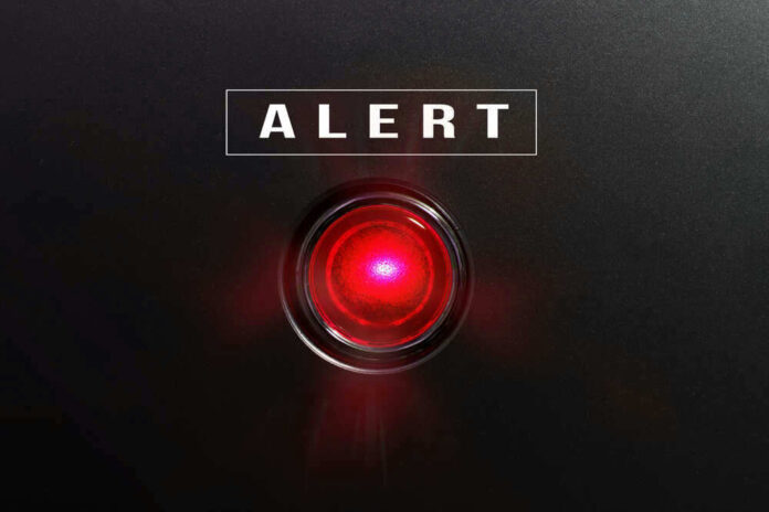 Red alert light against black background text ALERT