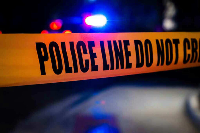 Police tape with flashing lights in the background