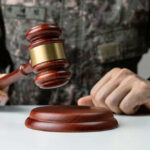 Military person holding gavel near desk