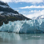Glacier with mountains and cloudy sky in background