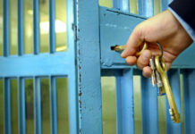 Hand unlocking blue metal door with keys