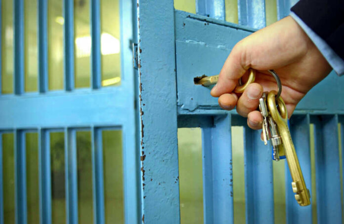 Hand unlocking blue metal door with keys