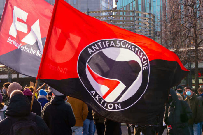Protest with Antifascist Action flags and people outdoors