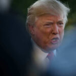 Donald Trump speaking outdoors, partially obscured