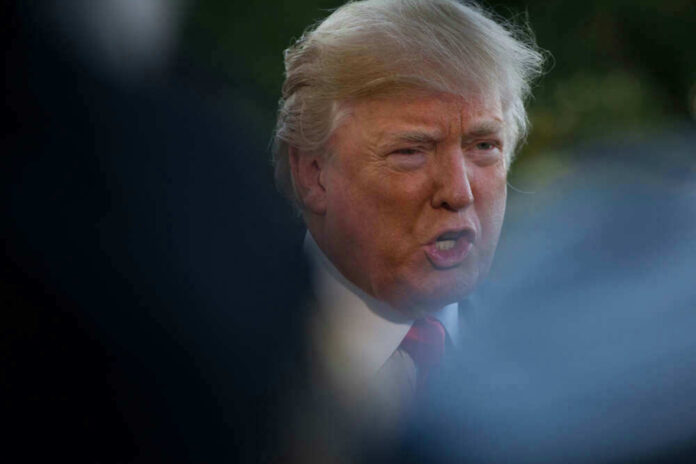 Donald Trump speaking outdoors, partially obscured