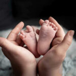 Baby feet cradled in adult hands.