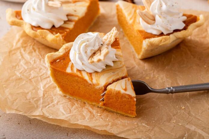 Slice of pumpkin pie topped with whipped cream and almond slivers