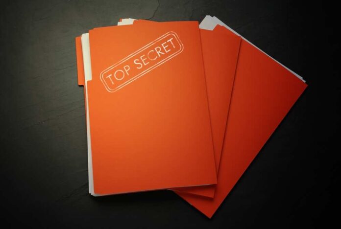 A stack of orange folders labeled TOP SECRET on a dark surface