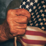 Pearl Harbor Success: Long-Lost Hero Identified Hand holding small American flag tightly