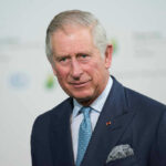 King Charles in a suit and tie smiling