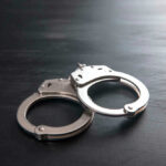 Metal handcuffs on a dark textured surface.