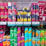 A variety of soda cans displayed on supermarket shelves