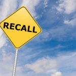 Yellow sign with RECALL text against blue sky.