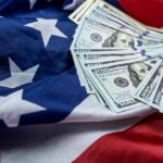 $12B Lifeline: Trump Sparks Liberal Outrage Stack of hundred dollar bills on an American flag