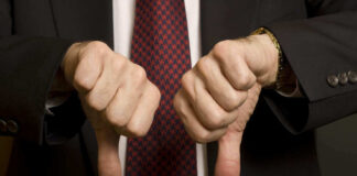 Two hands showing thumbs down in a suit.