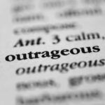 Close-up of a dictionary entry highlighting the word 'outrageous'