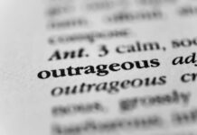 Close-up of a dictionary entry highlighting the word 'outrageous'