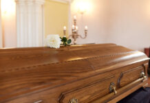 Bardot Dead: Legacy of Unfiltered Truths A wooden casket with a white rose placed on top in a solemn setting