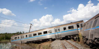 Derailed train car leaning off the tracks near a body of water