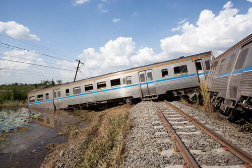 Derailed train car leaning off the tracks near a body of water