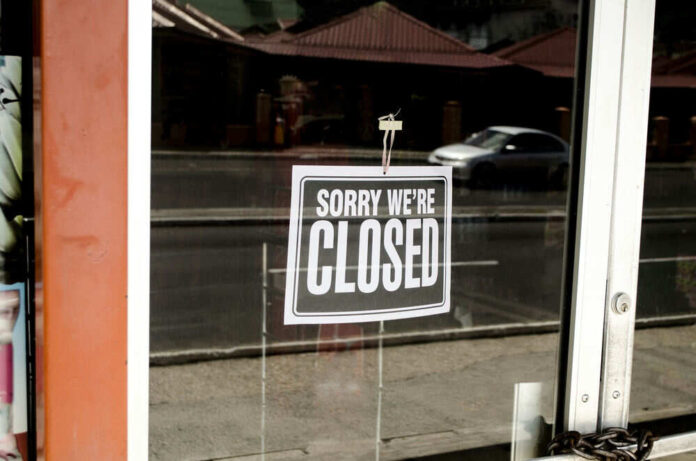 Closed sign hanging on a glass door