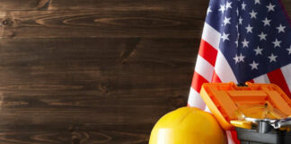 Yellow hard hat and tools with American flag.