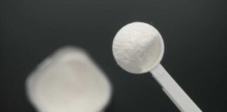 A measuring spoon filled with white powder against a blurred background
