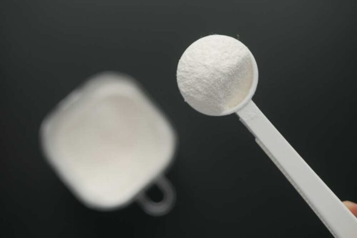 A measuring spoon filled with white powder against a blurred background